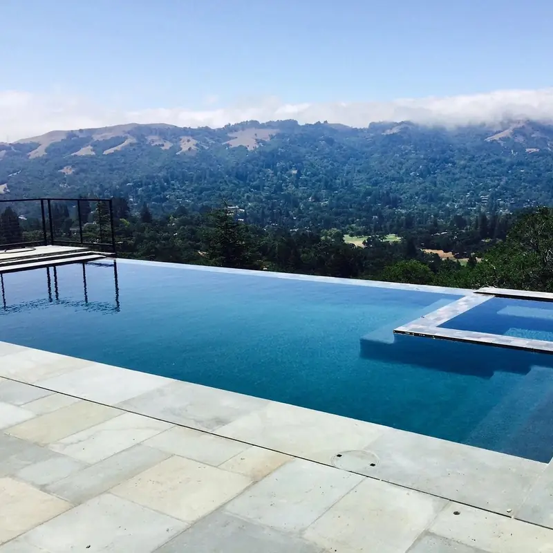 Infinity-edge pool and raised spa looking out over wooded hills